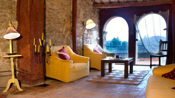 A cozy living room with yellow sofas, a wooden coffee table, and a stone wall. - CASA CARINA (Ullastret)