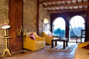 Ein gemütliches Wohnzimmer mit gelben Sofas, einem Holztisch und einer Steinwand.