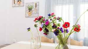 Una mesa de comedor con un florero de flores coloridas y dos jarrones de vidrio con tallos.