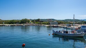 Un puerto deportivo con barcos amarrados, agua tranquila y un paisaje montañoso al fondo.