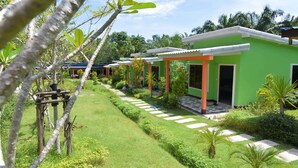 Una hilera de edificios verdes con un sendero de jardín bien cuidado y plantas tropicales.