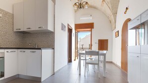 A modern kitchen with white cabinets, a tiled backsplash, and a dining area with a white table and chairs.