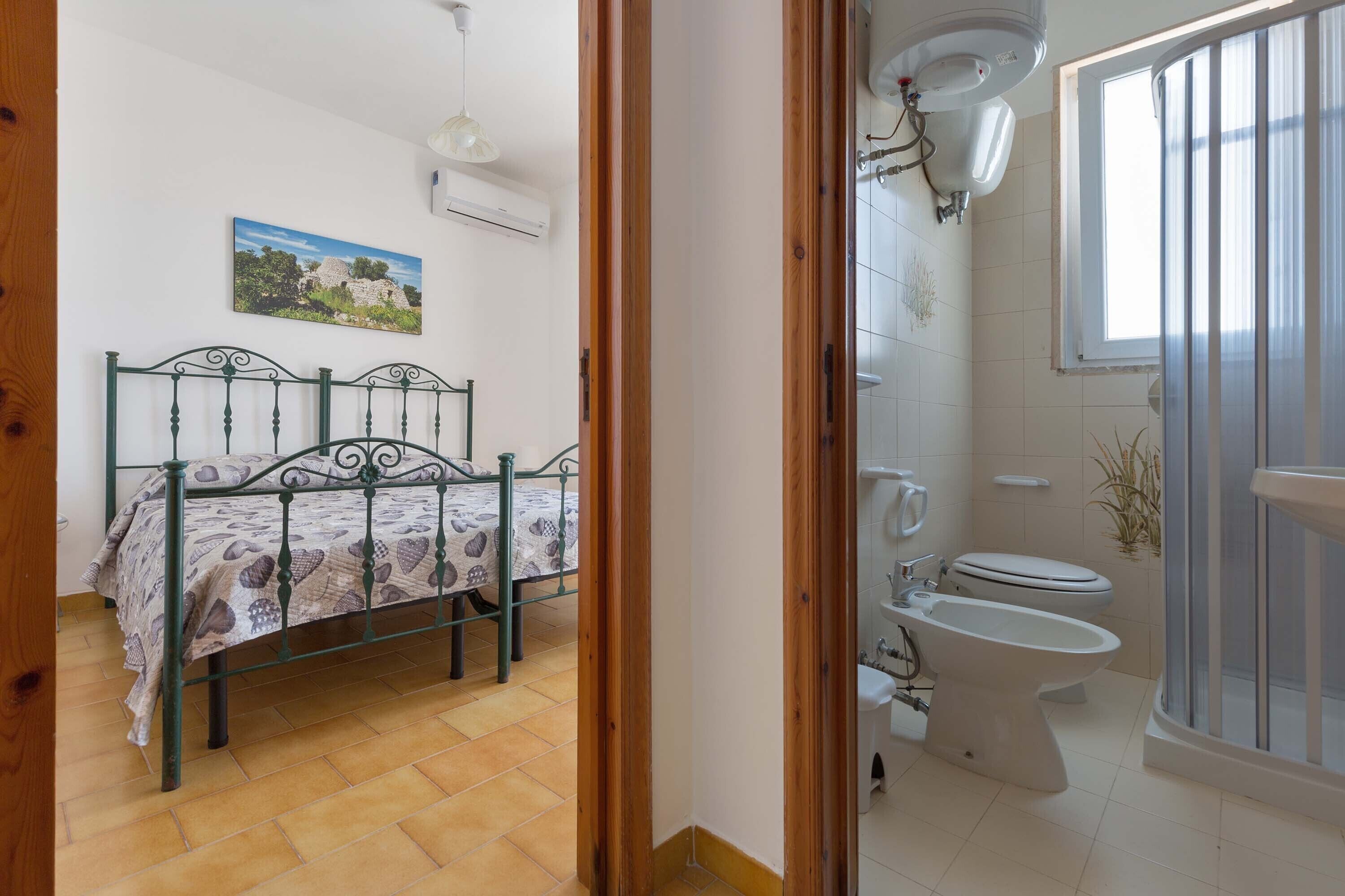 Un dormitorio con cama, y un baño con inodoro, bidé y ducha.