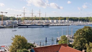 A harbor with a large sailing ship docked, surrounded by smaller boats and a marina. - HighEnd Travemünde - Whg 502 (Lübeck Travemünde)