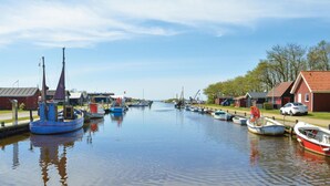 Een kanaal met aan beide oevers afgemeerde boten, omgeven door kleine huizen en een heldere lucht.