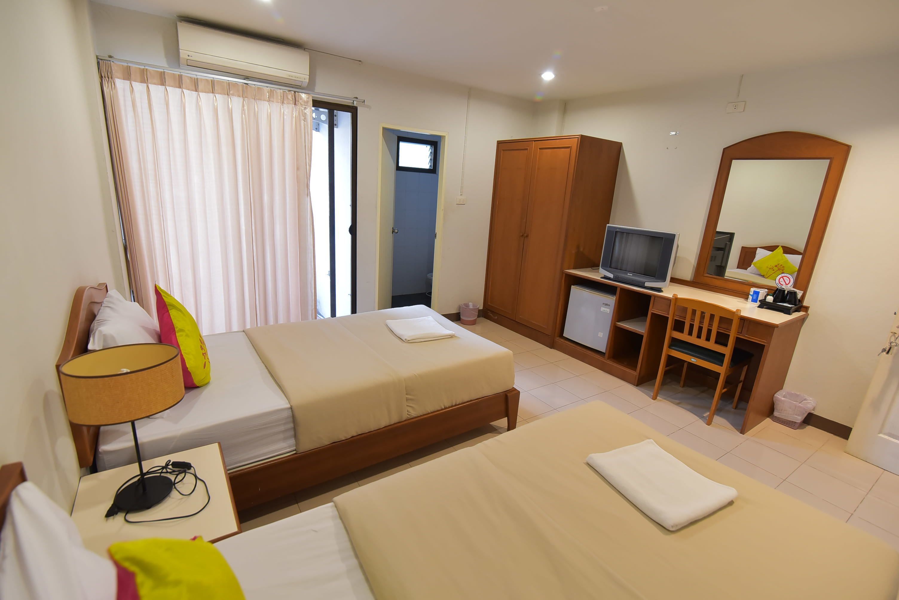 A hotel room with a bed, a desk with a computer, a television, and a wardrobe.