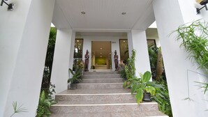 A staircase leading to a door with the number 25/1, flanked by potted plants and statues. - Kyongean Mansion 2 (Krabi)