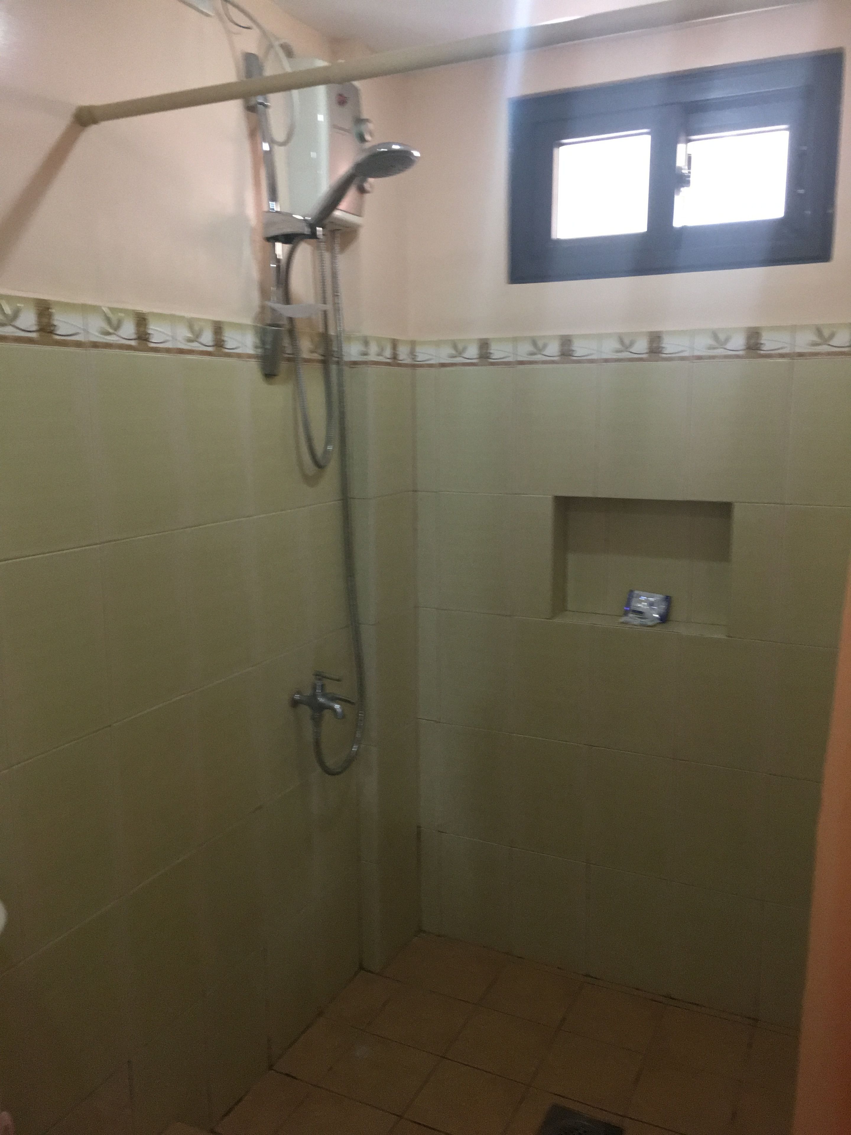 Un baño pequeño con azulejos, cabezal de ducha y ducha de mano.