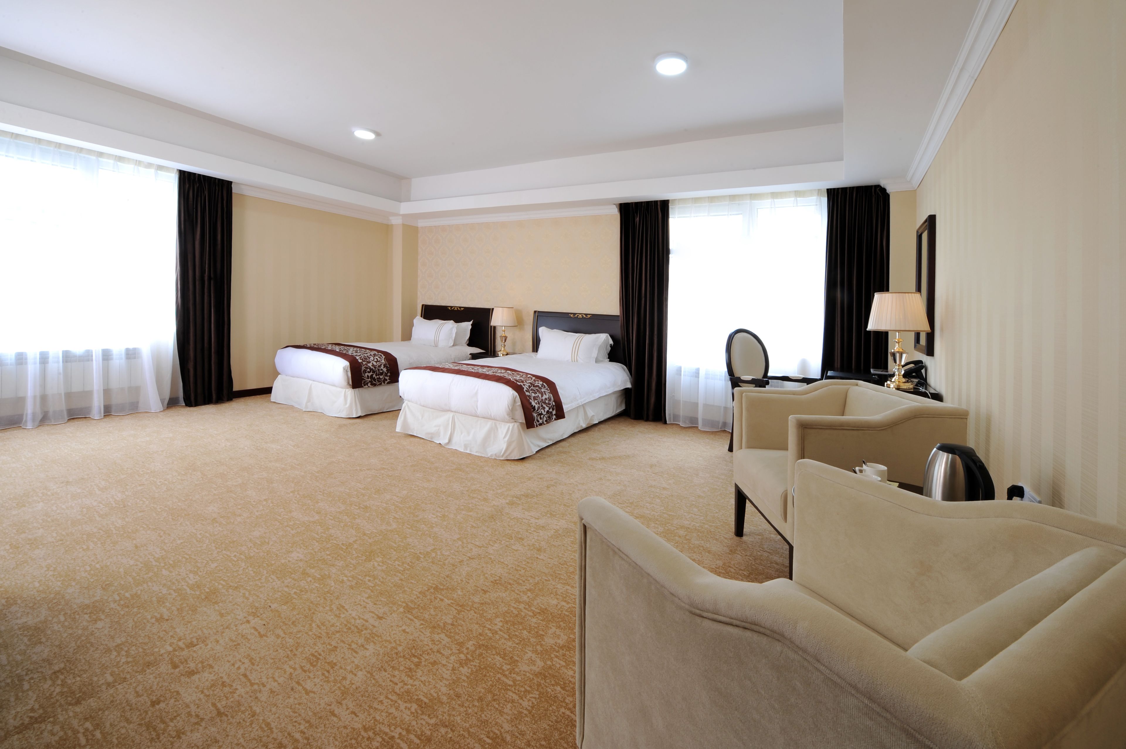 Habitación de hotel con dos camas, un sofá, un escritorio y una silla.