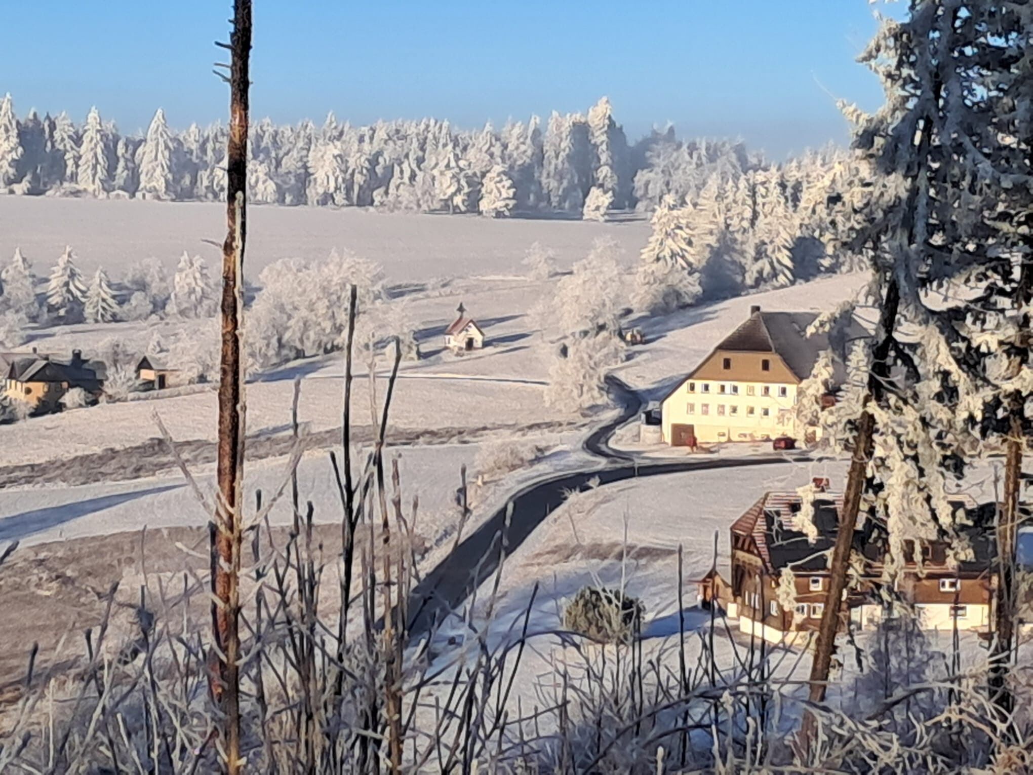 Een besneeerd landschap met een groot gebouw en kleinere huizen op de achtergrond.