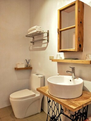 A compact bathroom with a toilet, bidet, sink, and a wooden cabinet with a mirror. - MacArthur (Tainan)
