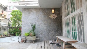 Un patio con muro de piedra, banco de madera, bicicleta y plantas en macetas.