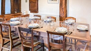 A dining table set for six with chairs, a wooden cabinet, and a clock on the wall. - Cozy home in Beauchene with WiFi (Beauchene)