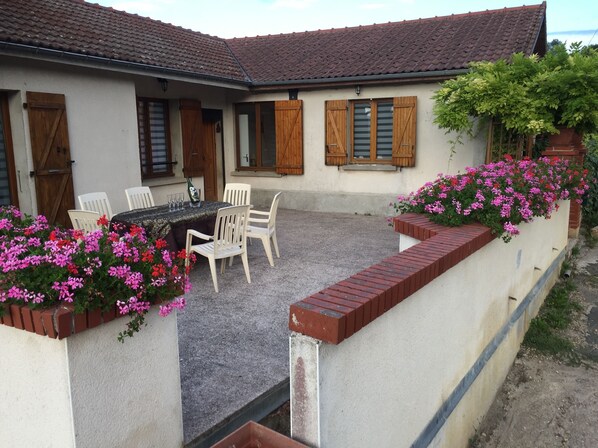 A courtyard with a table and chairs, surrounded by brick walls and flower boxes.