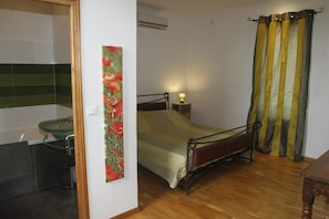 A bedroom with a bed, bedside table, and a green sink in the corner.