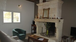 Un salon avec une cheminée, un canapé, un fauteuil, une table basse et un téléviseur.