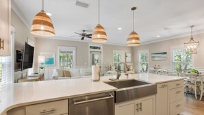 A modern kitchen with a central island, pendant lights, and a dishwasher.