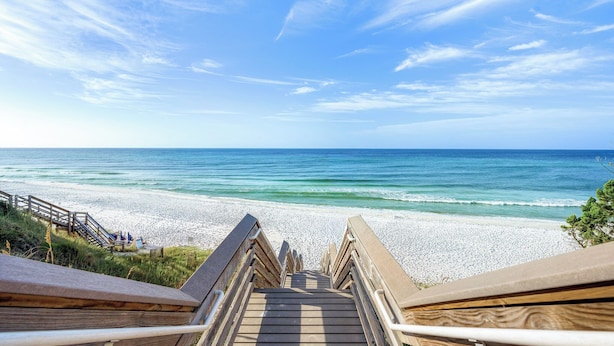 A wooden staircase leading to a beach with a clear sky.