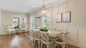 A dining area with a wooden table and chairs, a chandelier, and artwork on the walls.