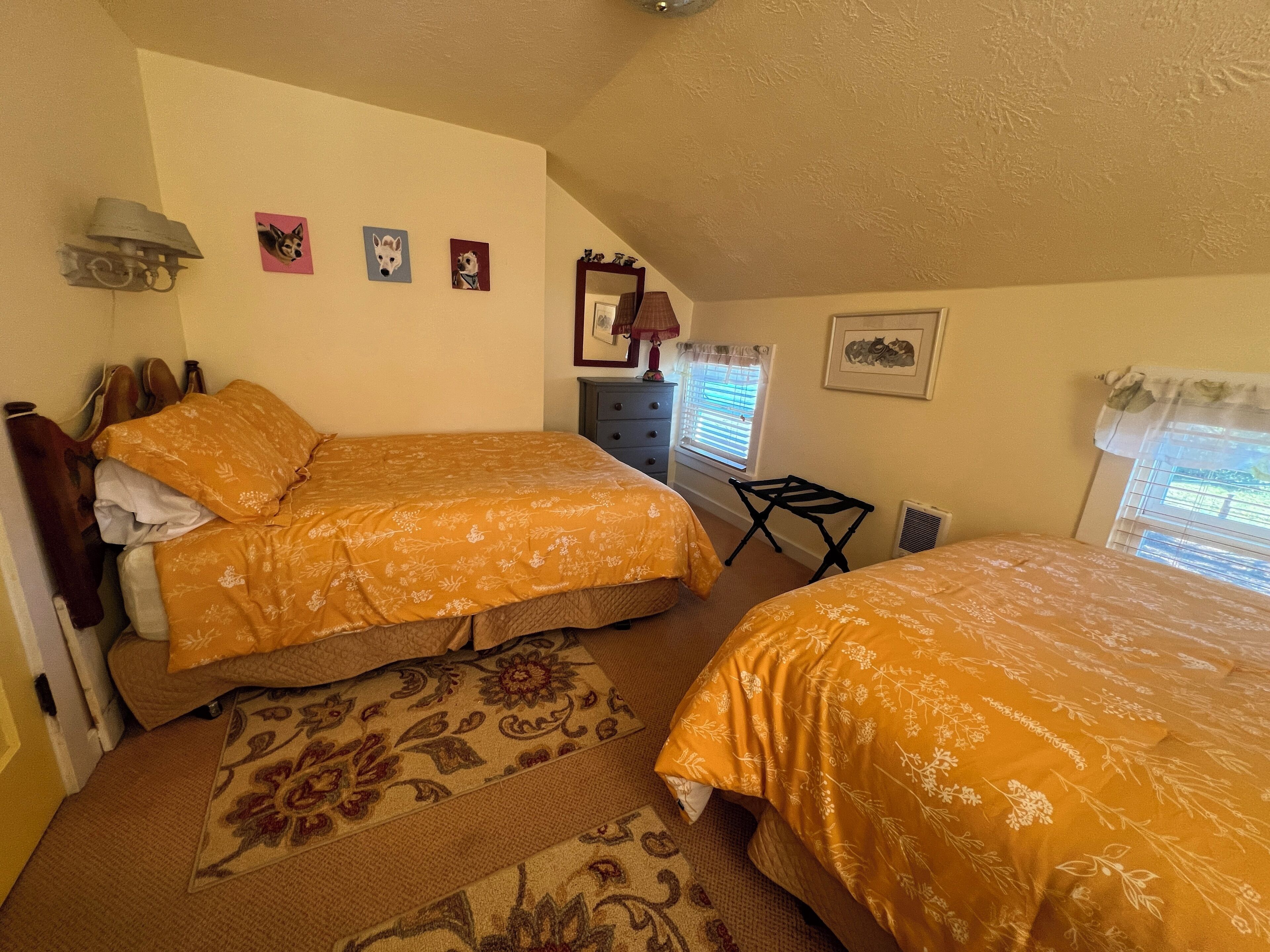 Une chambre avec deux lits, une commode, un miroir et une petite table.