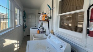Un cuarto de lavandería con lavadora, secadora y repisas con productos de limpieza.