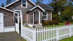 A two-story house with a white picket fence, a front porch, and a mailbox. - Adorable Cottage with Americana Theme, in the Heart of Gearhart. (Seaside)