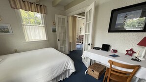 A bedroom with a bed, a desk, a chair, and a small table. - Adorable Cottage with Americana Theme, in the Heart of Gearhart. (Seaside)