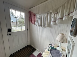 Enter a welcoming space with a white door, vertical paneling, and a cozy table with a lamp and decorative bowl.