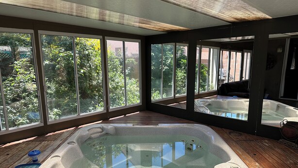 Ein Spa-Raum mit Whirlpool, großen Fenstern und Holzboden.
