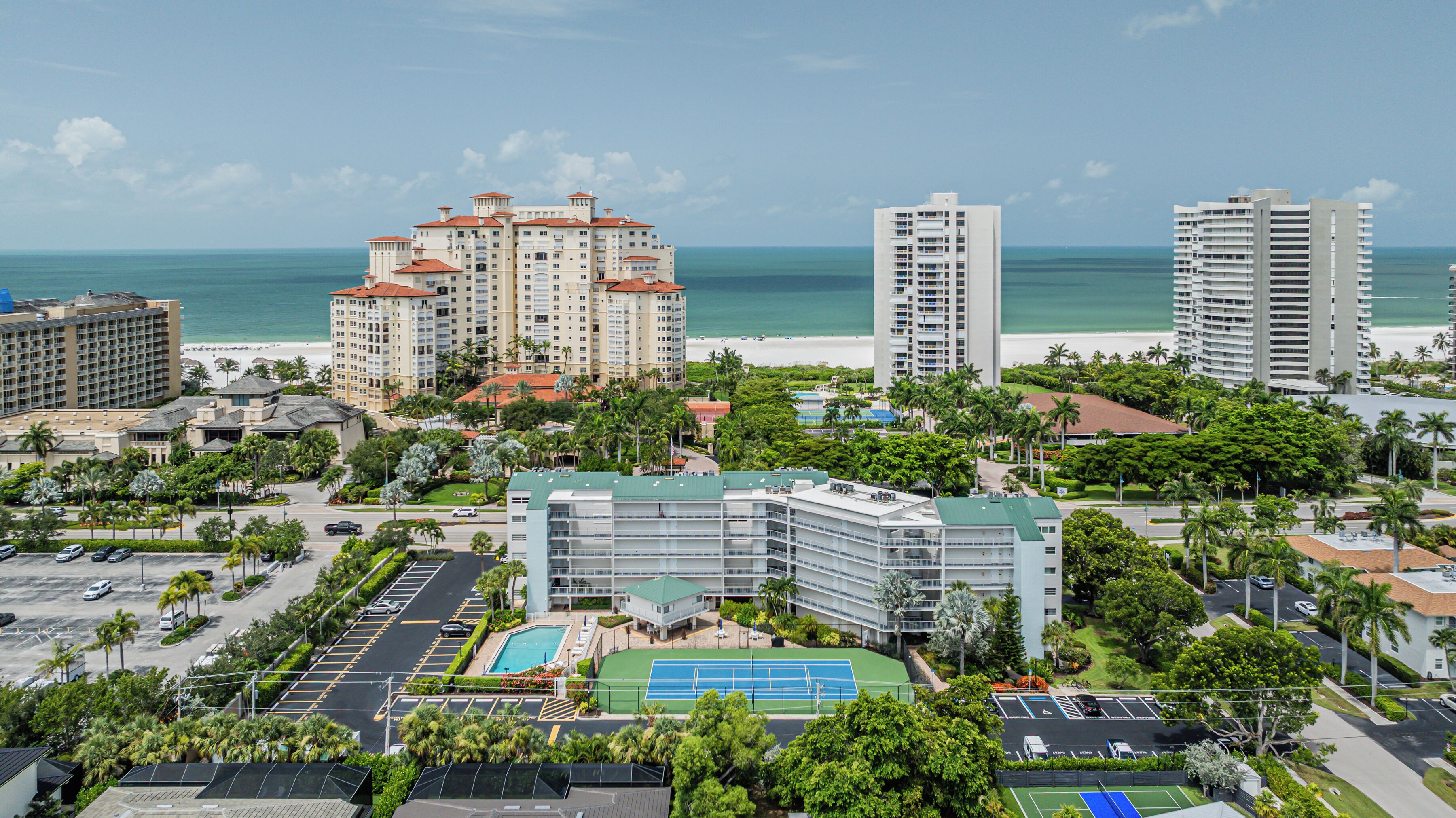 A high-rise hotel with multiple floors, a swimming pool, and a tennis court.