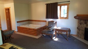 Une salle de bain avec une grande baignoire, un banc en bois, une chaise et une petite table.