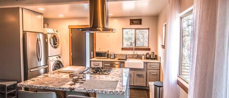 A modern kitchen with stainless steel appliances, granite countertops, and a large island with bar stools.