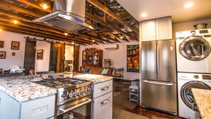Una cocina con estufa a gas, horno, refrigerador de acero inoxidable y lavadora y secadora integradas.