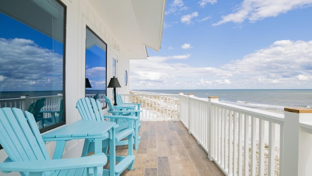 A balcony with blue Adirondack chairs, a table, and a lamp. - "The Pearl" GULF FRONT w/prvt heated pool, 12 bdrm /12.5bath "ALVacationRentals" (Gulf Shores)