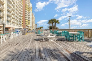A wooden deck with outdoor seating and a view of a tall hotel building. - Oceanfront Breath Taking View with Private Balcony - 2bd/2ba Condo in NMB (North Myrtle Beach)