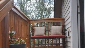 Une terrasse en bois avec un banc et un pot de fleurs.