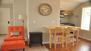 Un salon avec un canapé, une table et des chaises, une horloge et un poêle.
