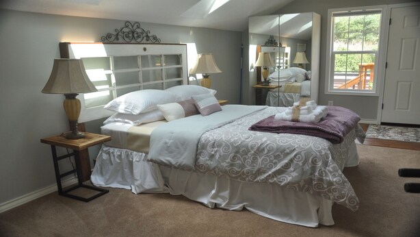 Une chambre à coucher avec un lit, des lampes de chevet, un miroir et une vue sur l’extérieur.