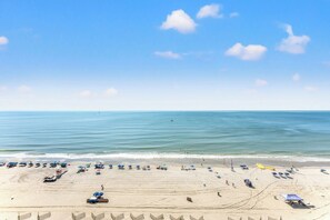 A beach with umbrellas, sun loungers, and a clear sky. - Cozy and Bright Condo with Jacuzzi Tub, Lazy River | Crescent Shores - S 1211 (North Myrtle Beach)