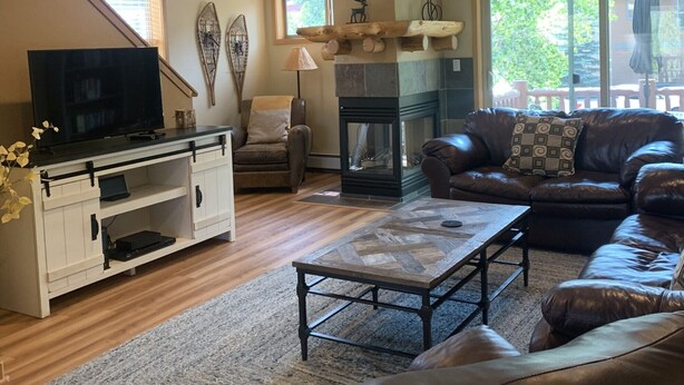 A living room with a fireplace, leather sofas, a TV, and a wooden entertainment unit.