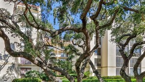 Un immeuble doté de nombreux balcons et d’un jardin planté d’arbres.