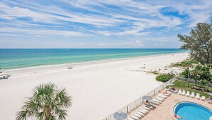 A beach view with a pool area, lounge chairs, and a clear sky. - Gulf Front Corner Balcony - Sand Castle III 501 (Indian Shores)