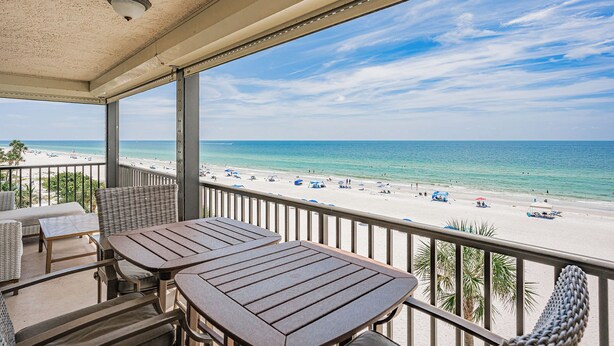 A balcony with a view of a beach, outdoor furniture, and a ceiling light fixture. - Gulf Front Corner Balcony - Sand Castle III 501 (Indian Shores)