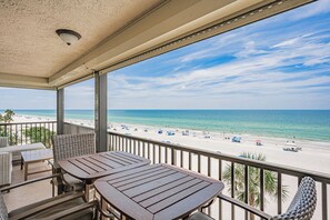 Un balcone con vista sulla spiaggia, arredi da esterno e una lampada a soffitto.