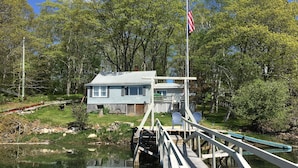A house with a dock extending into a lake, surrounded by trees.
