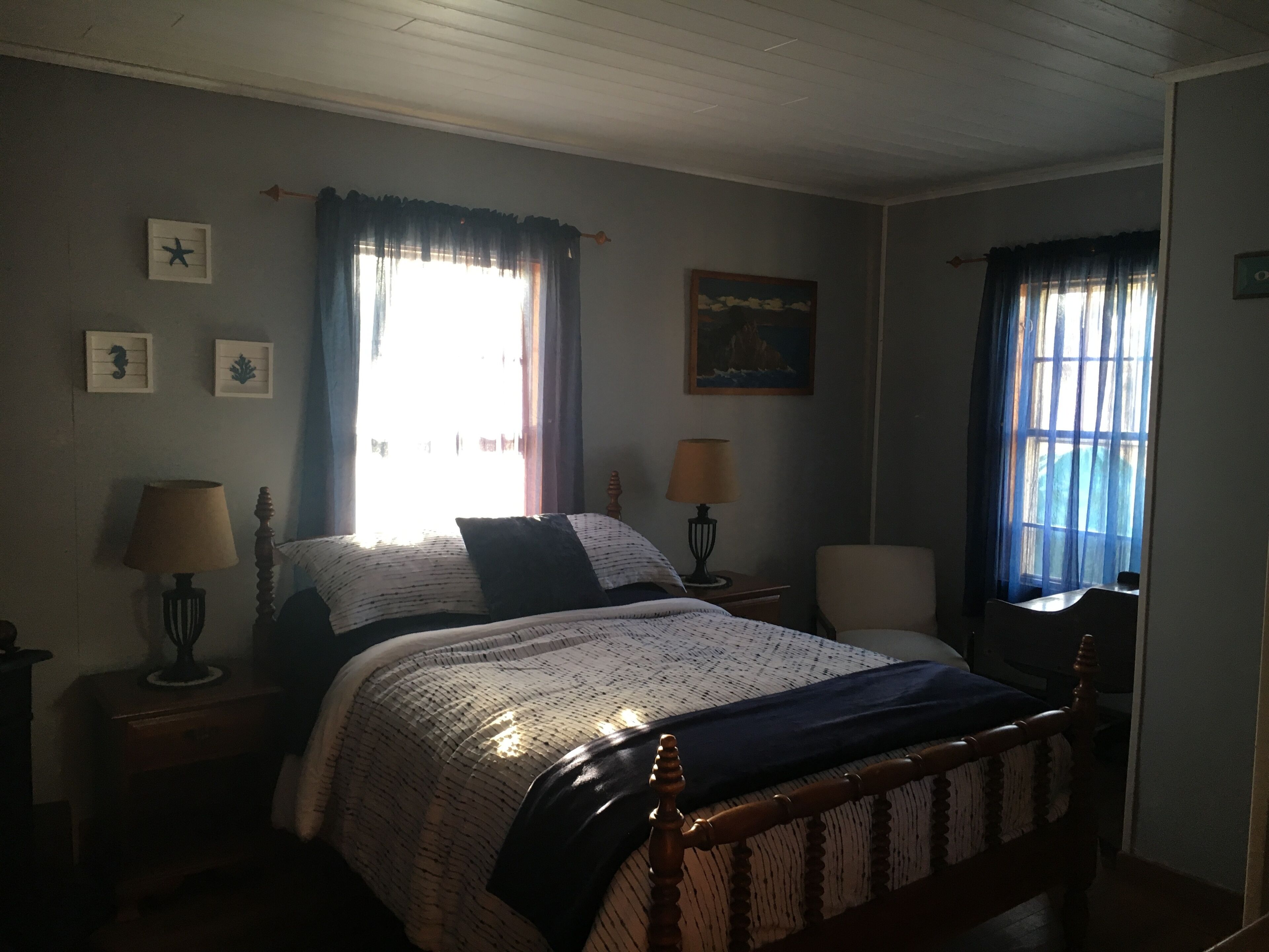 Ein Schlafzimmer mit einem Bett, zwei Nachttischen, zwei Lampen, einem Sessel und einem Bild an der Wand.