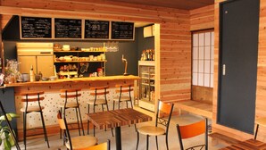 A cozy restaurant with wooden walls, a bar area, and several tables and chairs. - Bar & Hostel MONDO - Hostel (Osaka)