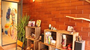 A room with wooden shelves displaying books, decorative items, and a painting on the wall. - Bar & Hostel MONDO - Hostel (Osaka)