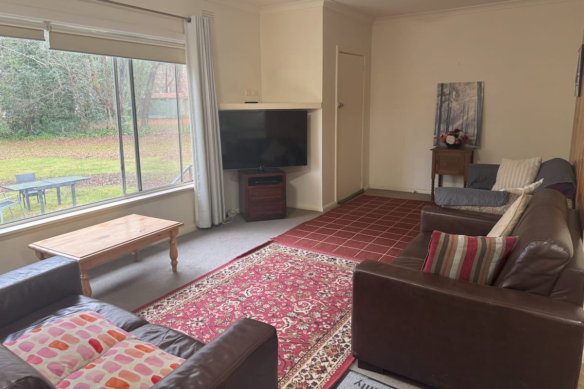 A living room with a sofa, a coffee table, a TV, and a large window.