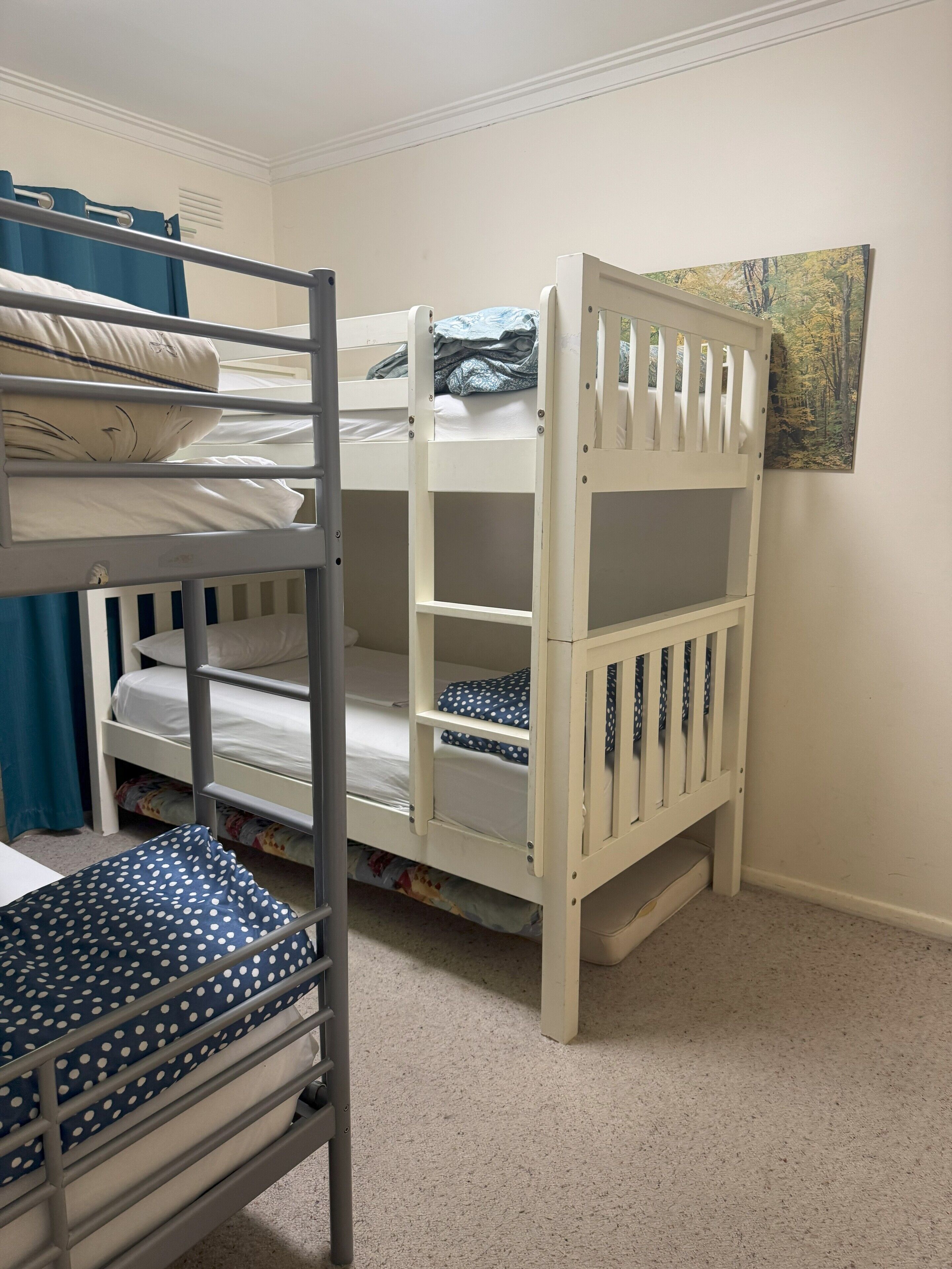 A bunk bed with a lower bunk and a top bunk, a small desk with a chair, and a painting on the wall.